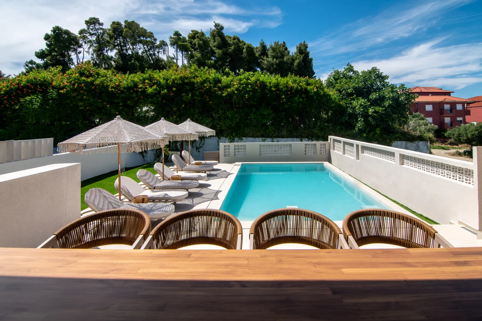 Rattan chairs looking over the pool and garden hedge