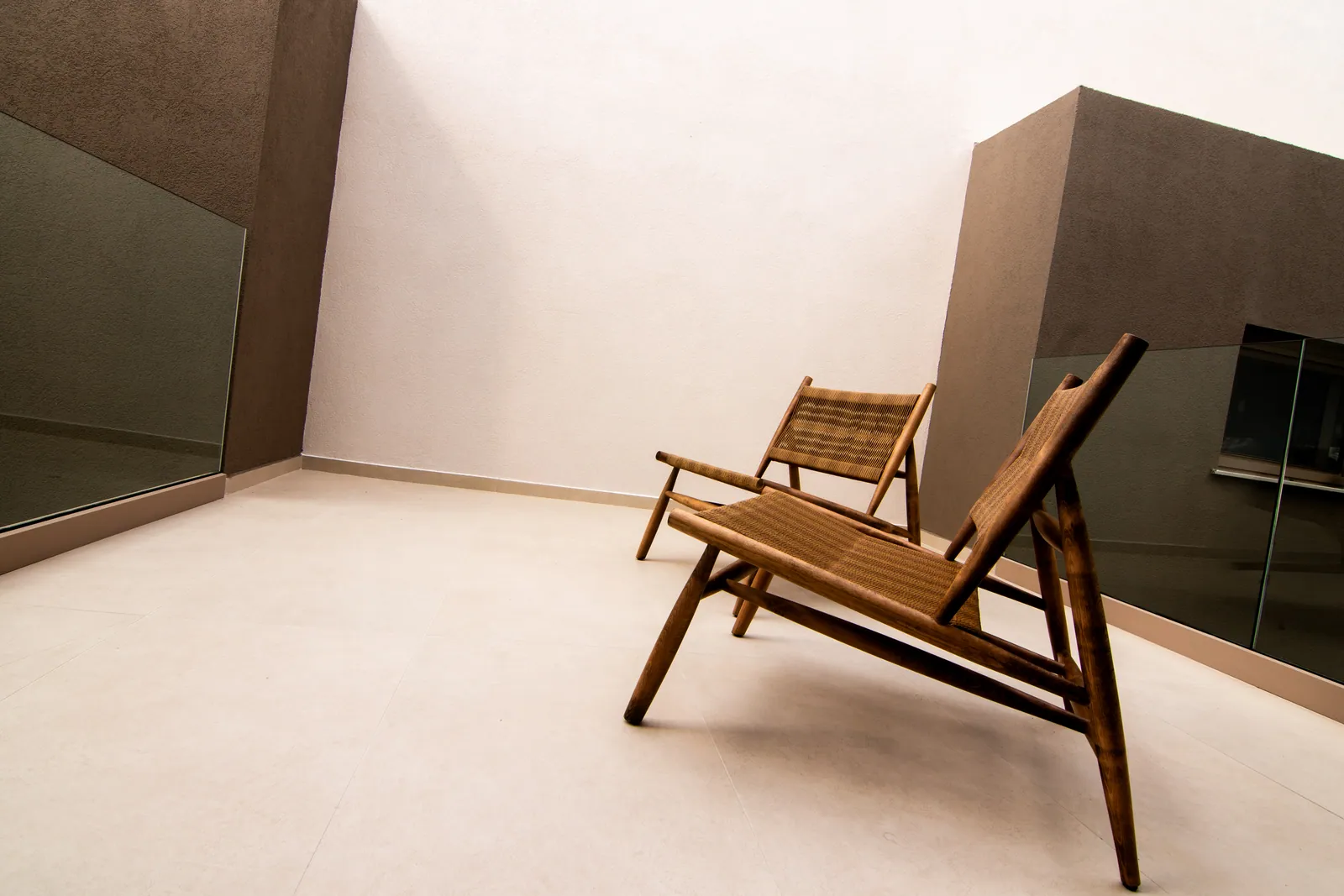 Two woven lounge chairs in a sunlit courtyard