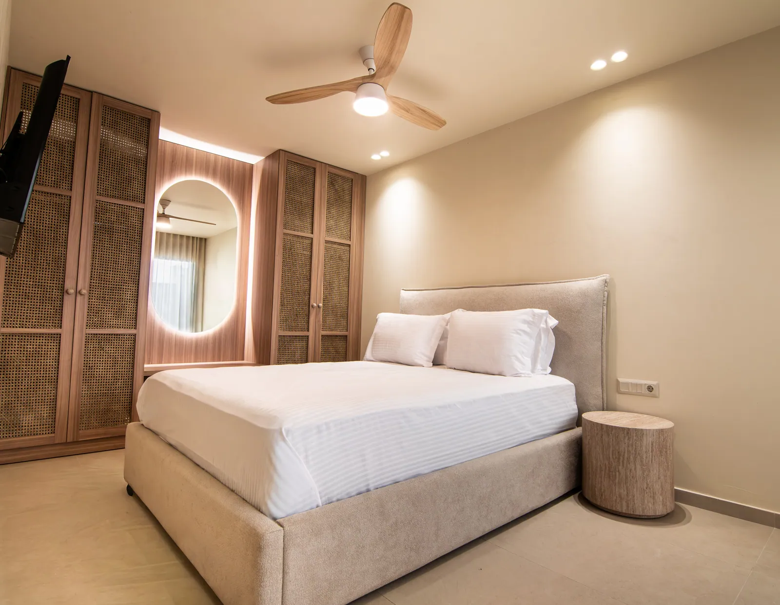 Bedroom with an upholstered bed and a backlit round mirror