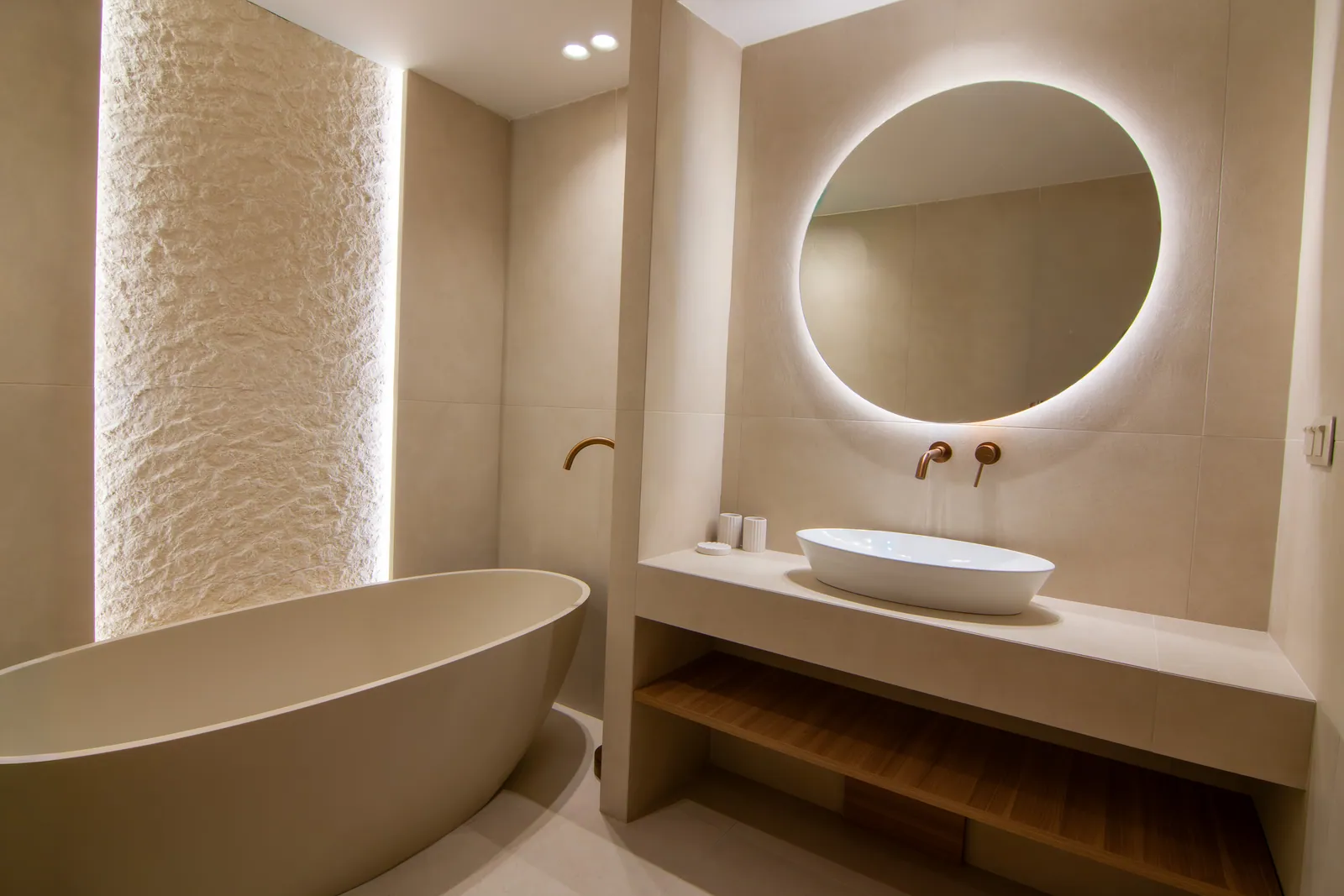 Bathroom with a freestanding tub and textured stone wall