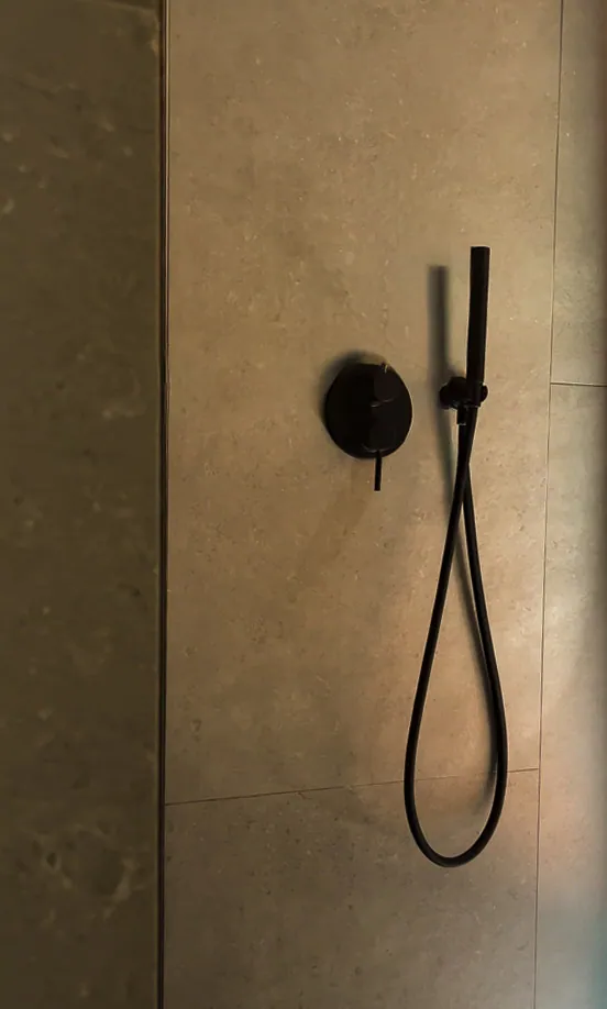 Black shower fittings against stone tiles