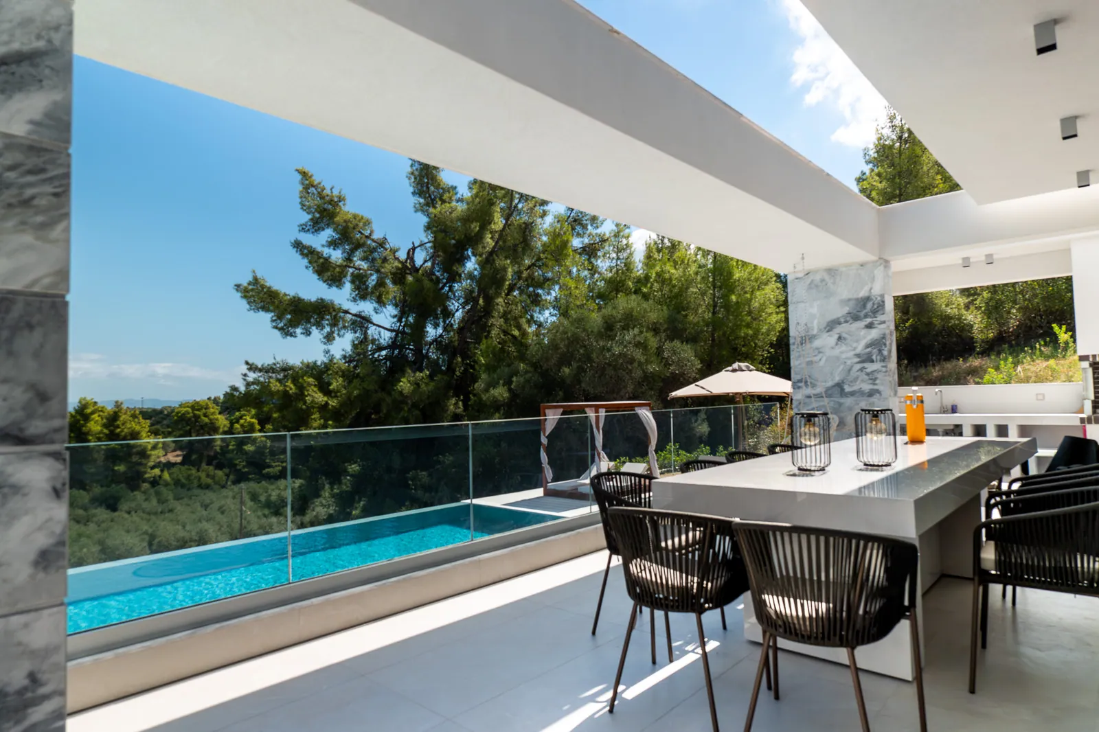 Outdoor dining beside a glass balustrade and the pool