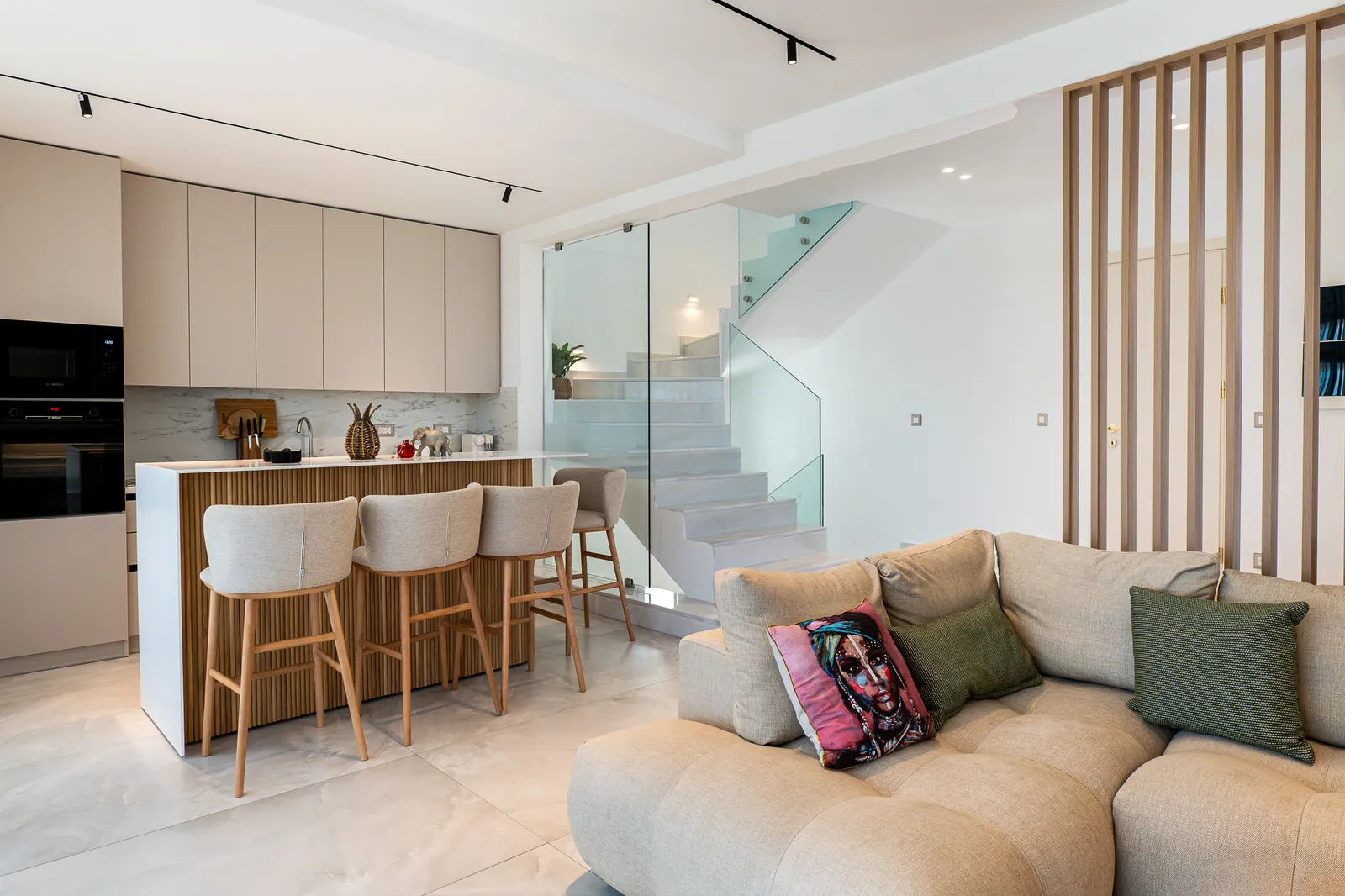 Open kitchen and lounge with a glass staircase