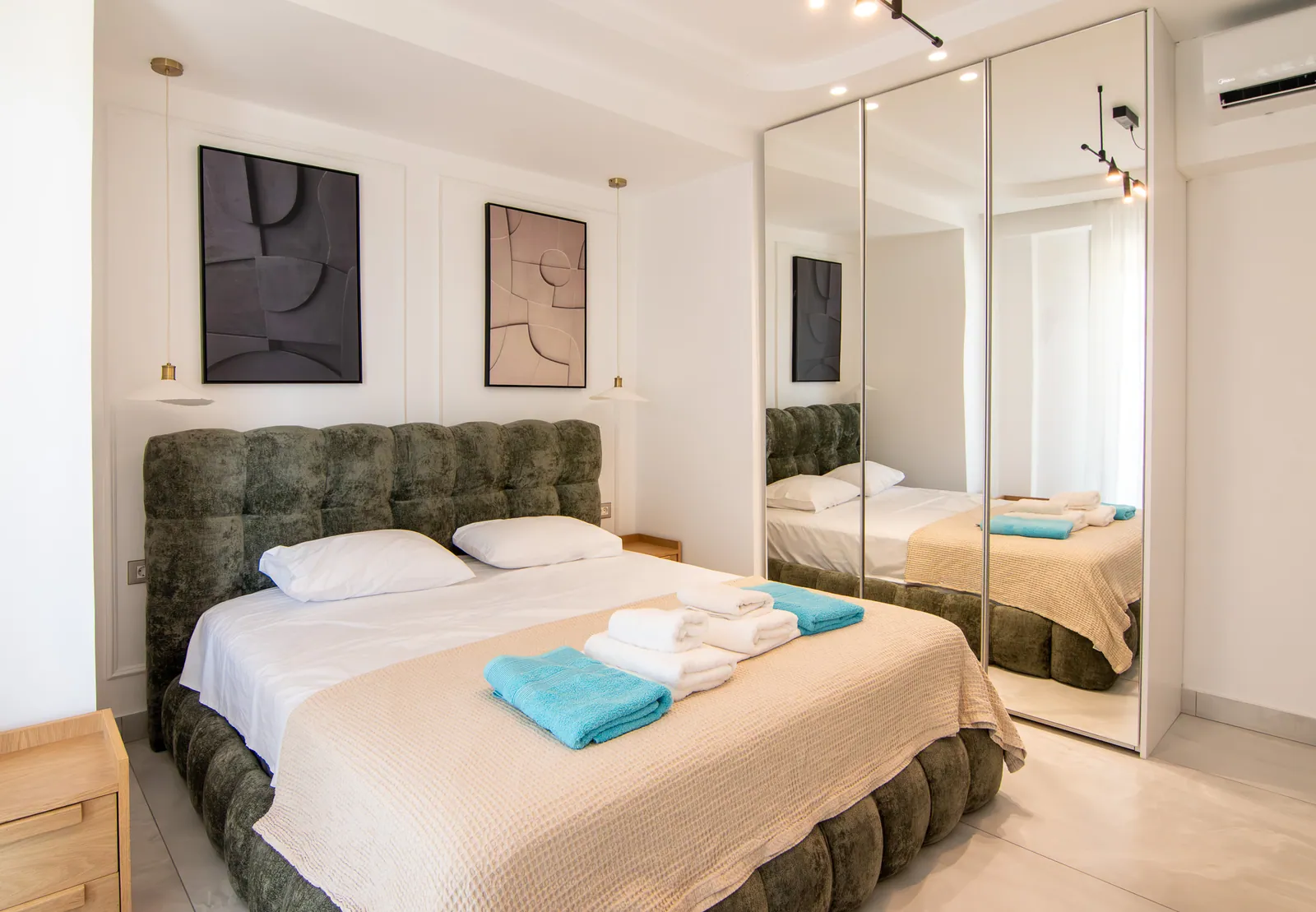 Bedroom with a tufted green headboard and abstract art